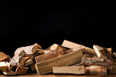 Photo of Cut firewood on table against black background