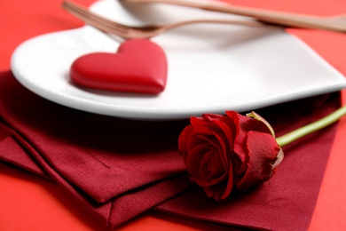 Photo of Elegant table setting for romantic dinner on red background, closeup. Valentine's day celebration
