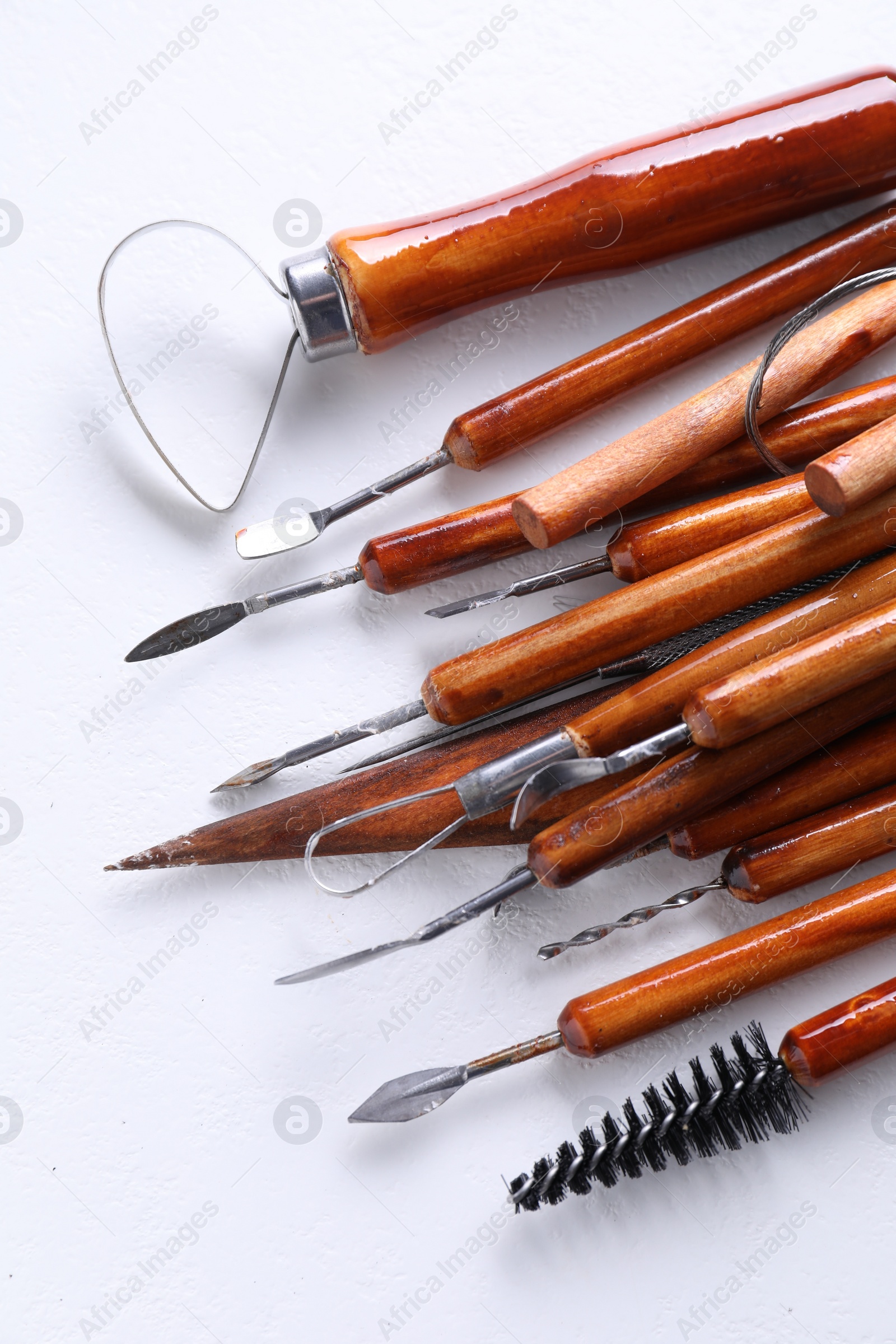 Photo of Set of different clay crafting tools on white textured table, flat lay