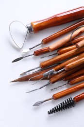 Photo of Set of different clay crafting tools on white textured table, flat lay