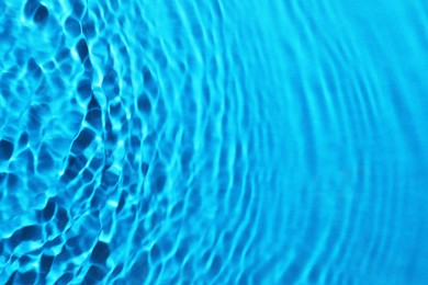 Image of Rippled surface of clear water on light blue background, closeup