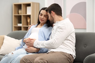 Pregnant woman with her husband on sofa at home