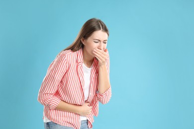 Woman suffering from nausea on blue background, space for text. Food poisoning