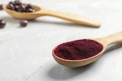 Photo of Spoon with acai powder on light table, closeup