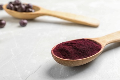 Spoon with acai powder on light table, closeup