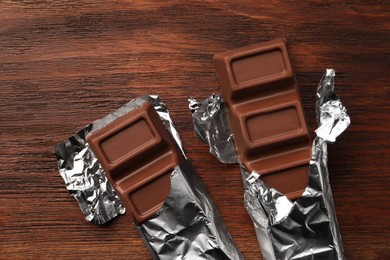 Photo of Tasty chocolate bars on wooden table, flat lay