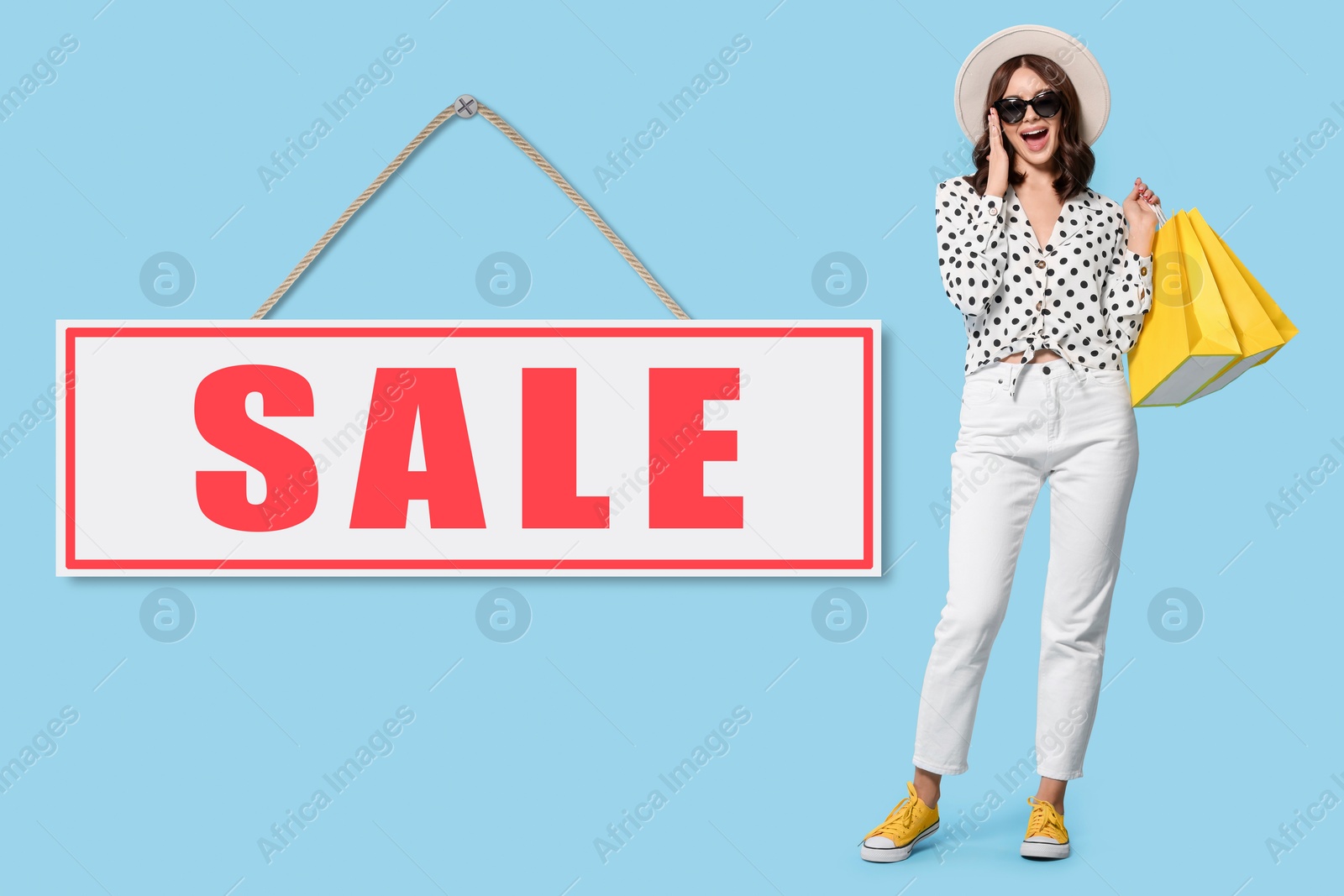 Image of Beautiful young woman with paper shopping bags and Sale sign on light blue background