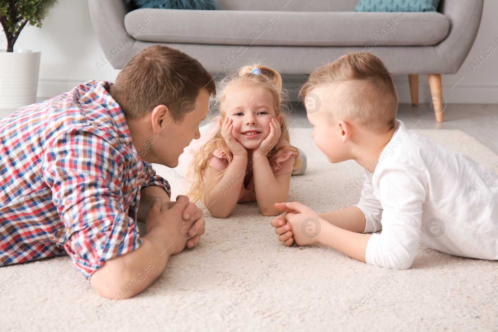 Photo of Cute little children and their father lying on cozy carpet at home