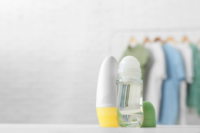 Photo of Different deodorants on white table in room. Space for text