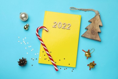 Photo of Yellow planner and Christmas decor on light blue background, flat lay. Planning for 2022 New Year