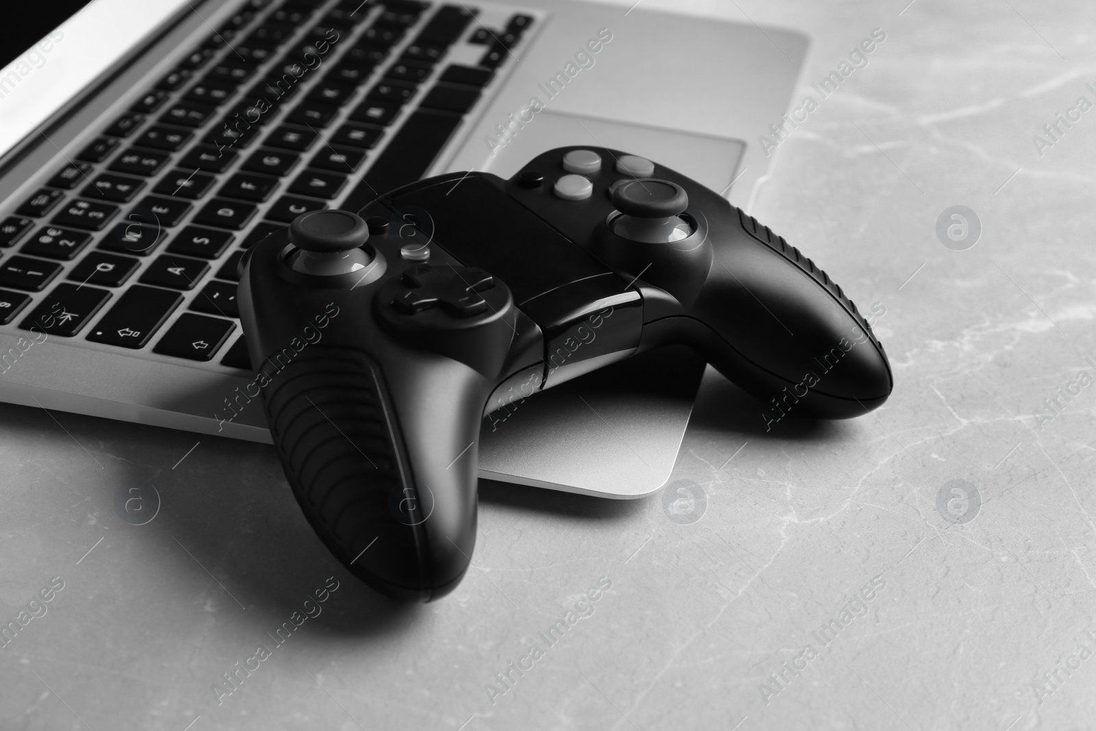 Photo of Video game controller and laptop on grey table