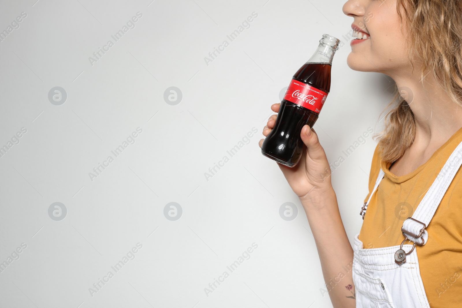 Photo of MYKOLAIV, UKRAINE - NOVEMBER 28, 2018: Young woman with bottle of Coca-Cola on white background, space for text