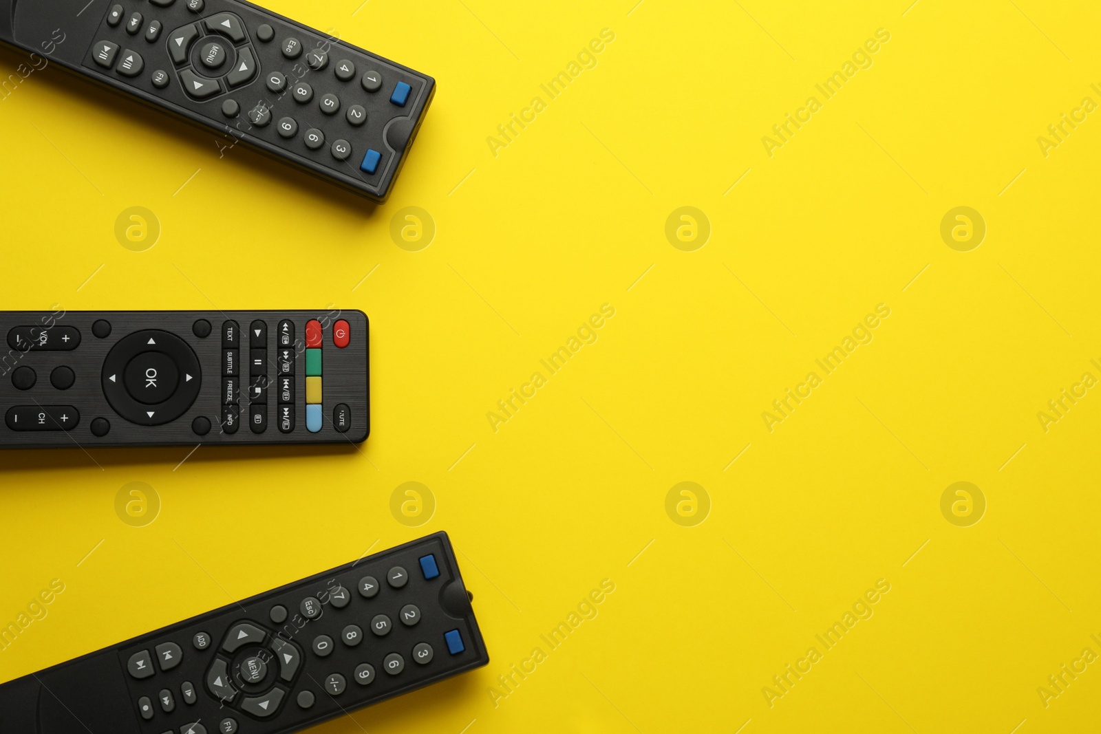 Photo of Remote controls on yellow background, flat lay. Space for text