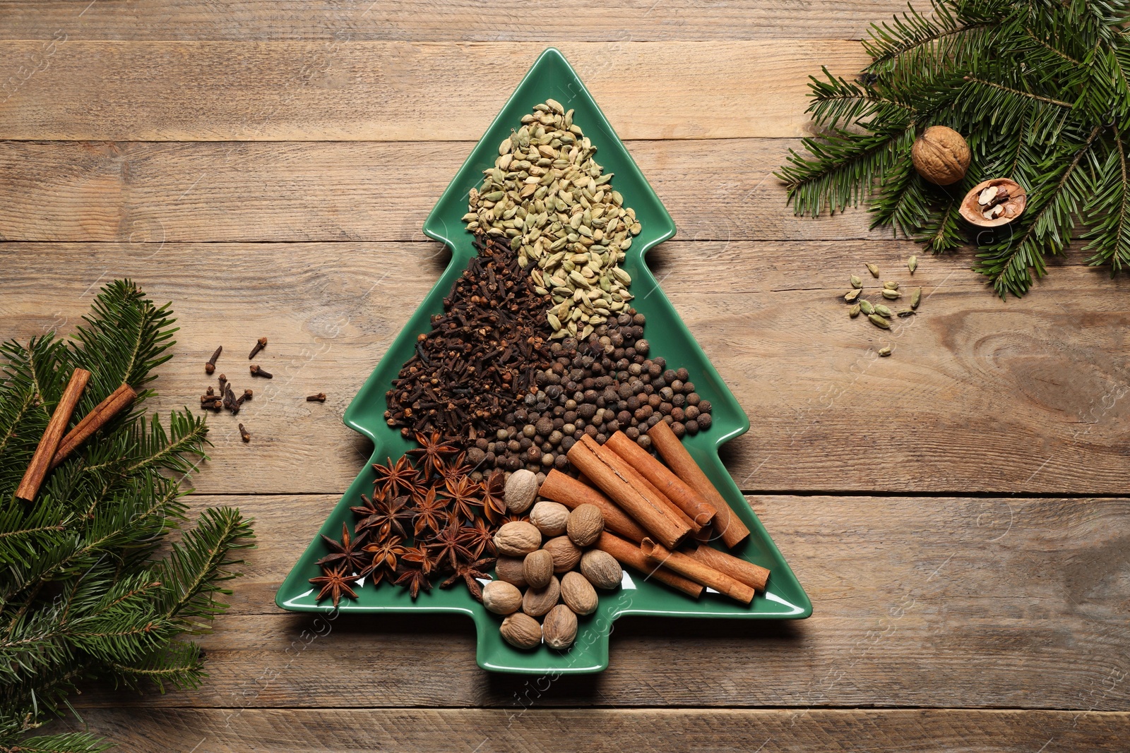 Photo of Different spices, nuts and fir branches on wooden table, flat lay