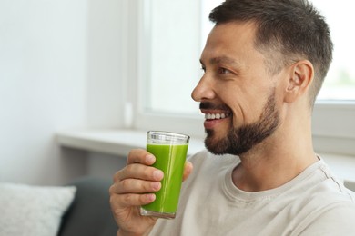 Photo of Man drinking delicious juice at home, space for text