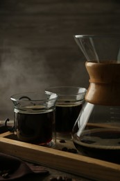 Photo of Glass chemex coffeemaker with coffee and beans on wooden table