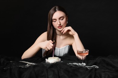 Photo of Fashionable photo of attractive young woman lighting candle on her Birthday cake against black background