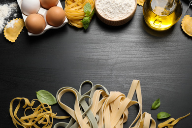 Photo of Flat lay composition with different types of pasta on black wooden table. Space for text