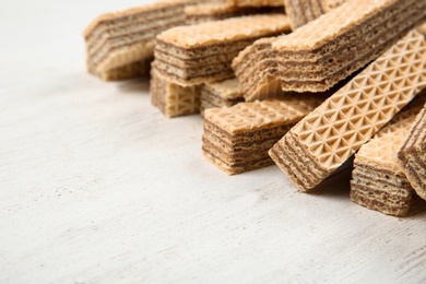 Delicious crispy wafers on white wooden table, closeup. Space for text