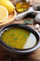 Bowl with lemon sauce on wooden table, closeup. Delicious salad dressing