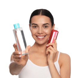 Photo of Young woman with bottles of micellar water on white background