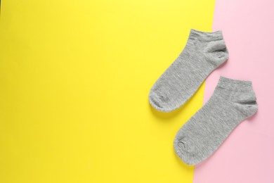 Pair of grey socks on colorful background, flat lay. Space for text