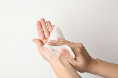 Photo of Woman cleaning hand with antiseptic wipe on light background, closeup. Virus prevention