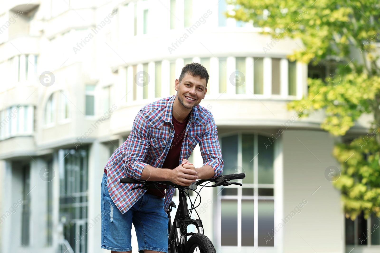 Photo of Handsome man with modern bicycle on city street