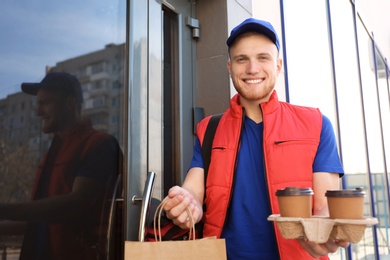 Photo of Portrait of courier with order at door. Food delivery service