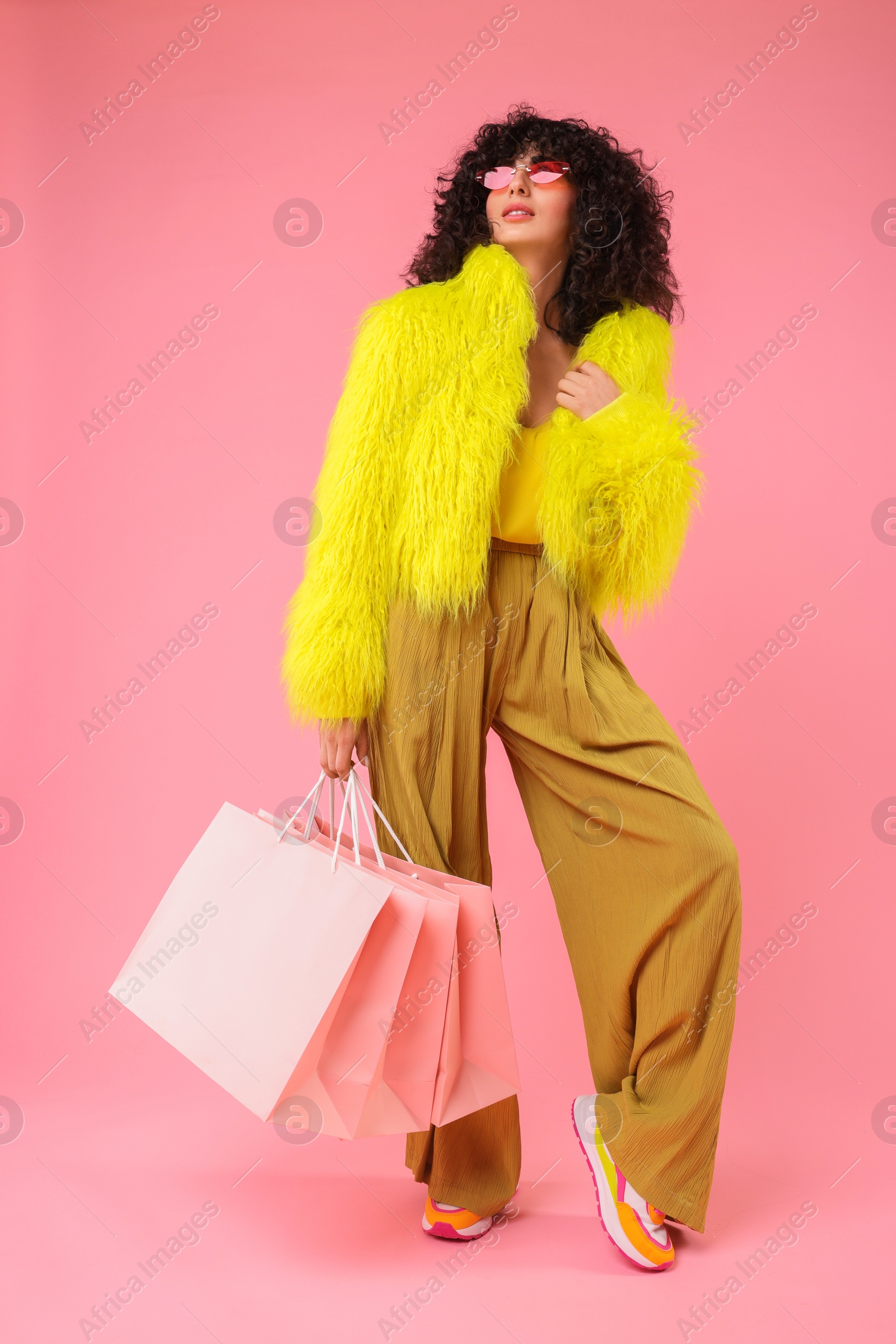 Photo of Happy young woman with shopping bags on pink background