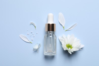 Photo of Bottle of cosmetic serum, flowers, petals and sea salt on light blue background, flat lay