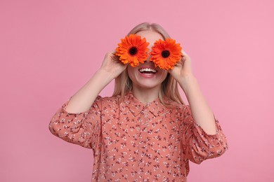 Photo of Woman covering her eyes with spring flowers on pink background