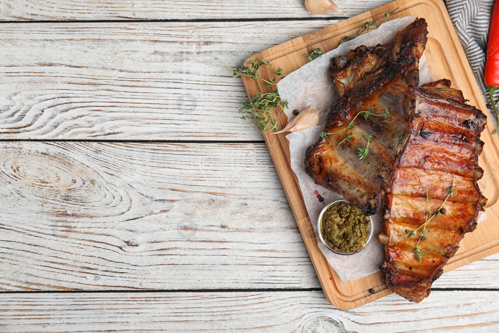 Photo of Tasty grilled ribs served on white wooden table, flat lay. Space for text