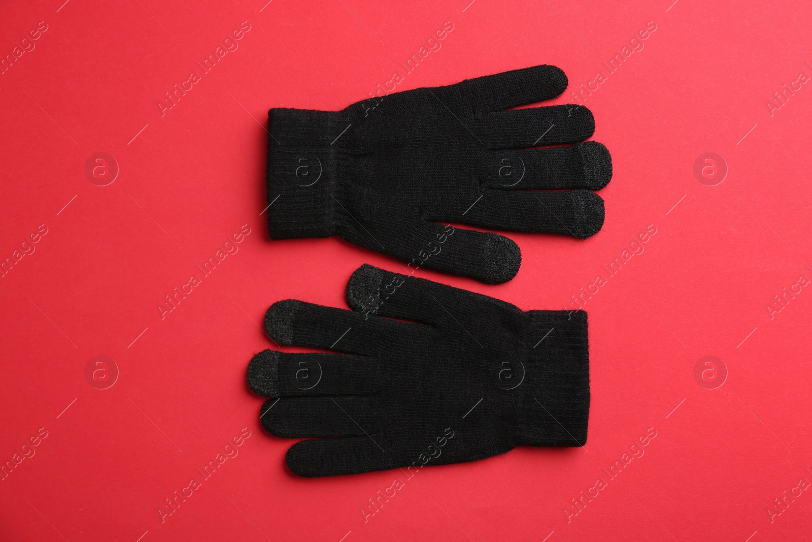 Photo of Pair of stylish woolen gloves on red background, flat lay