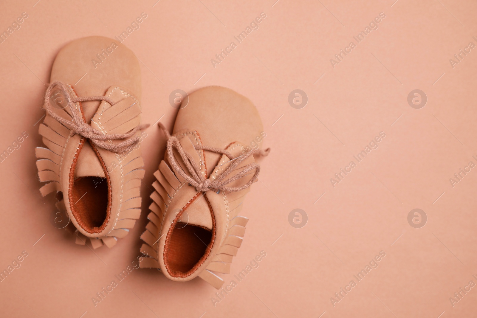 Photo of Cute baby shoes on brown background, flat lay. Space for text