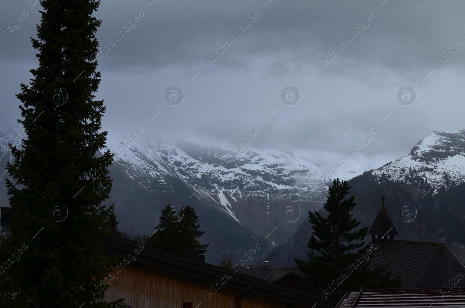 Photo of Picturesque view of cottage village and mountains covered with fog