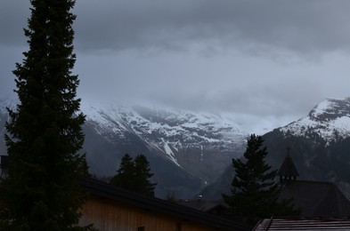 Photo of Picturesque view of cottage village and mountains covered with fog