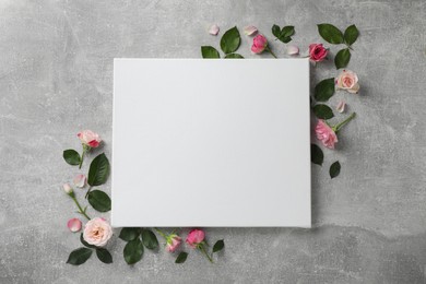 Photo of Flat lay composition with blank canvas and beautiful roses on grey background. Mockup for design