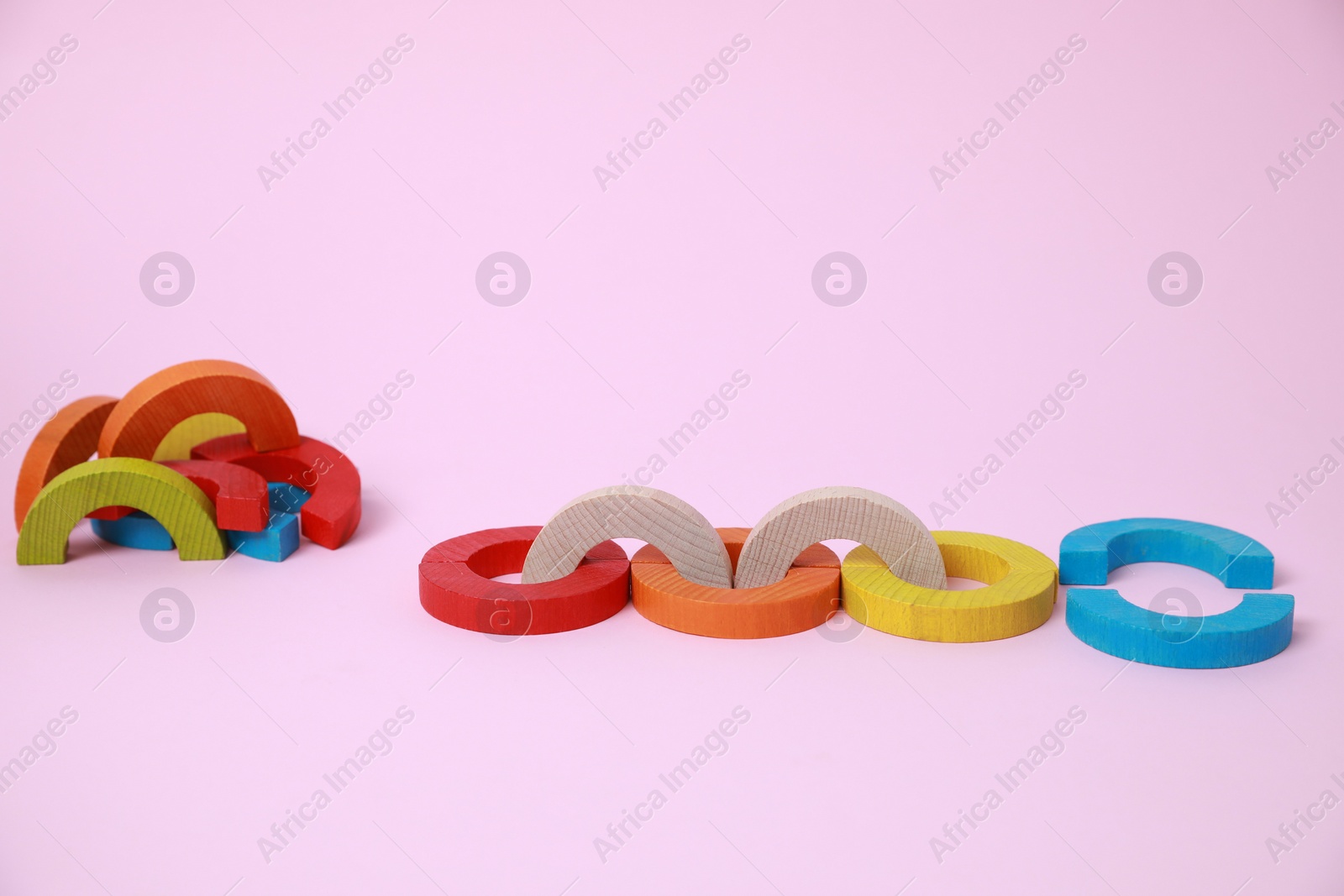 Photo of Colorful wooden pieces of playing set on pink background. Educational toy for motor skills development