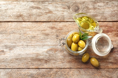 Beautiful composition with oil and ripe olives on wooden table, top view