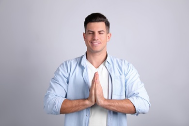 Photo of Man meditating on light background. Stress relief exercise