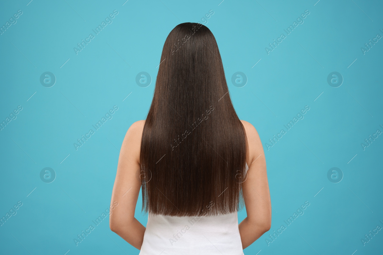 Photo of Woman with healthy hair after treatment on light blue background, back view