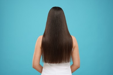 Photo of Woman with healthy hair after treatment on light blue background, back view