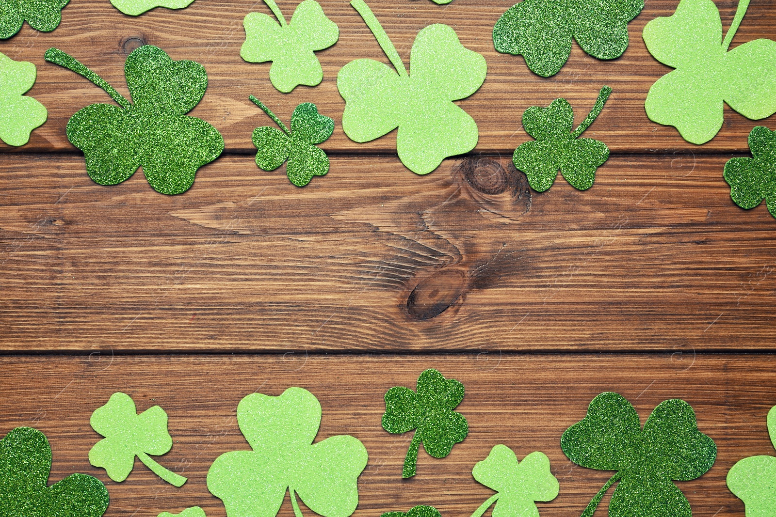 Photo of Decorative clover leaves on wooden background, flat lay with space for text. St. Patrick's Day celebration