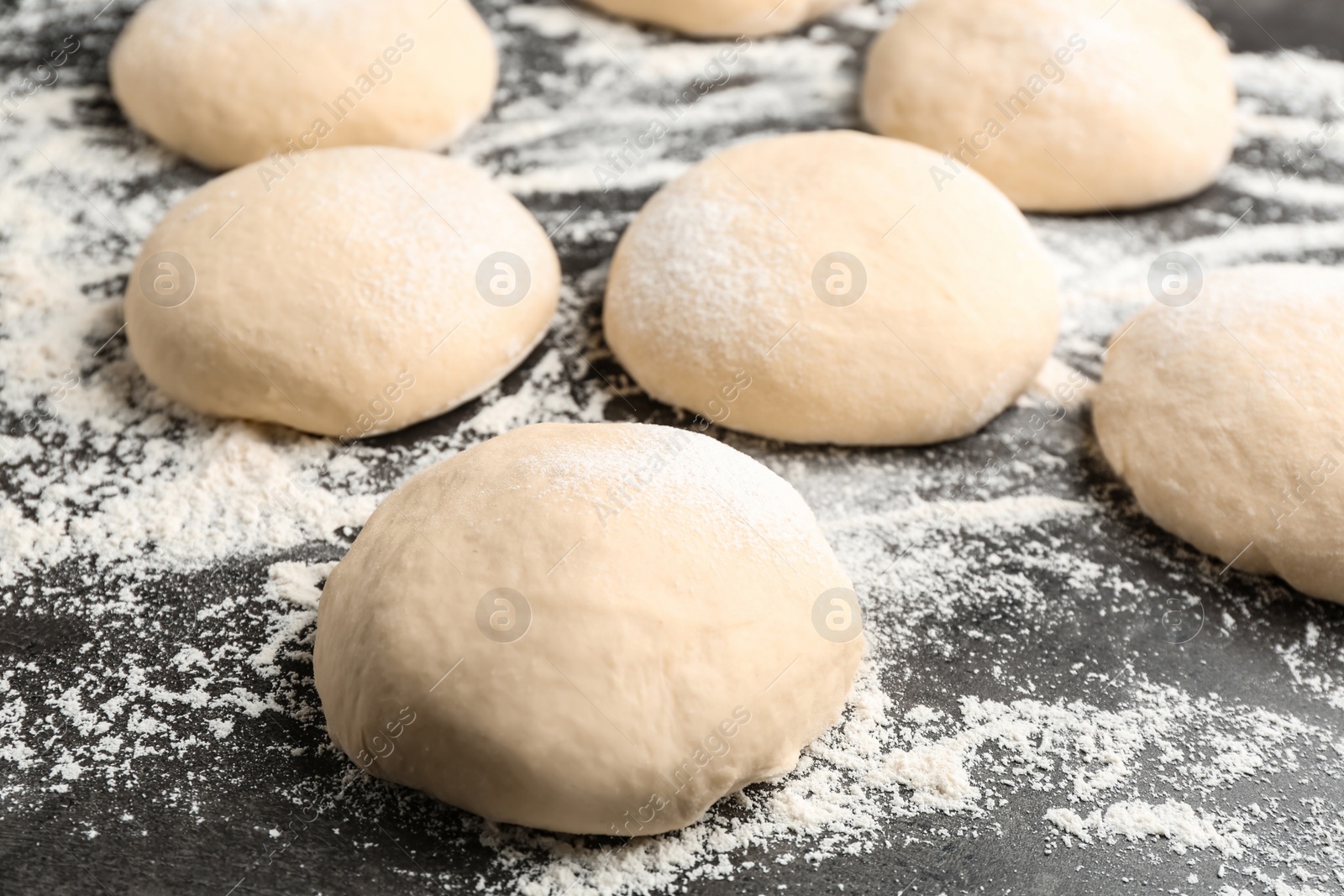 Photo of Raw wheat dough and flour on grey table