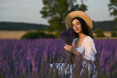 Beautiful young woman with bouquet sitting in lavender field