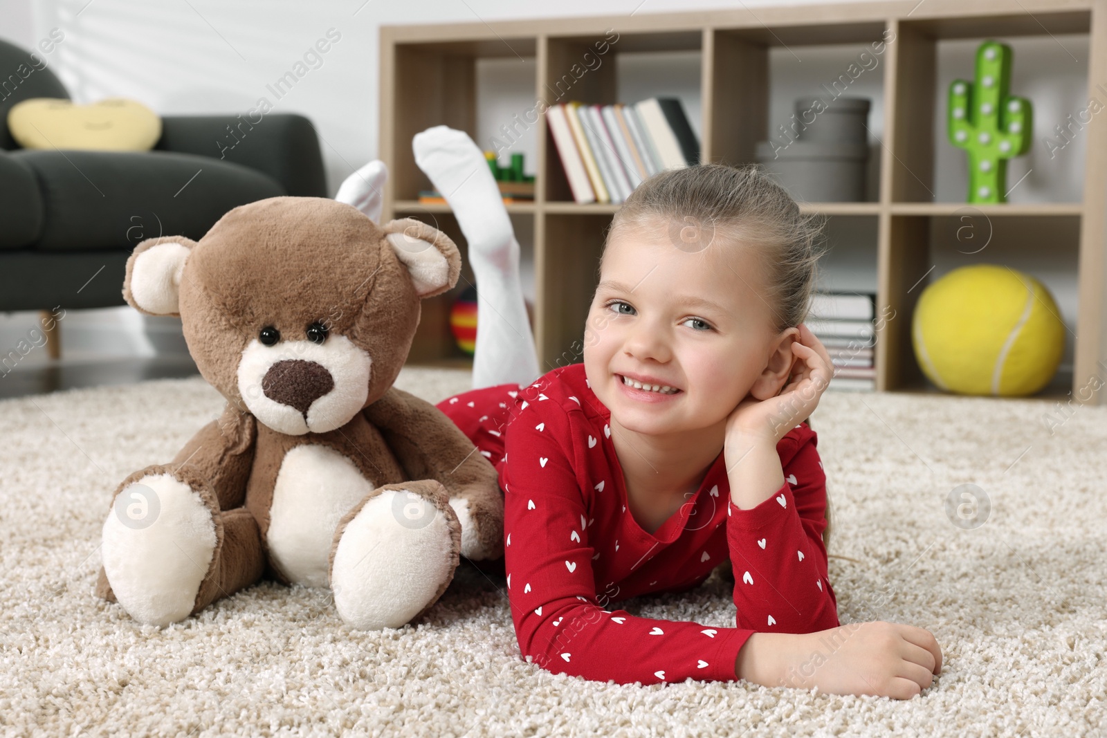 Photo of Cute little girl playing with teddy bear at home