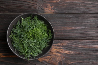 Bowl of fresh dill on wooden table, top view. Space for text