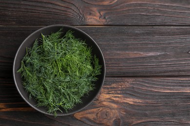 Photo of Bowl of fresh dill on wooden table, top view. Space for text