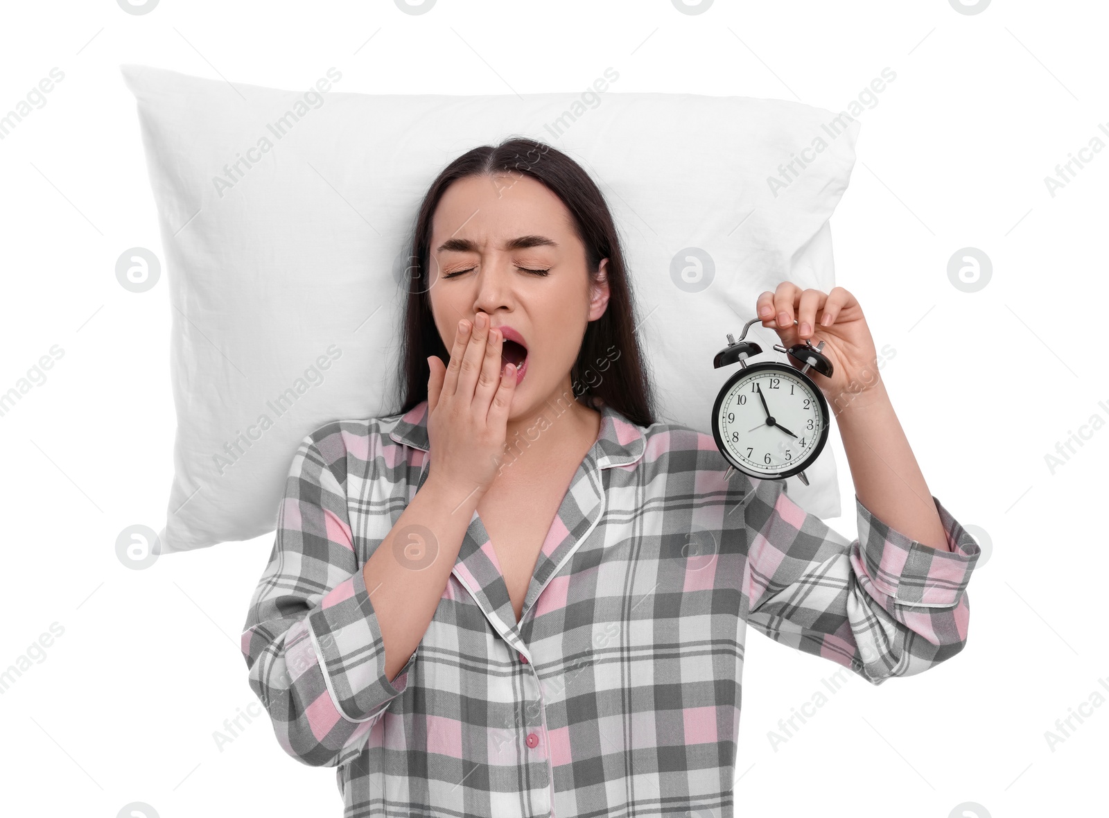 Photo of Tired young woman with alarm clock and pillow yawning on white background. Insomnia problem